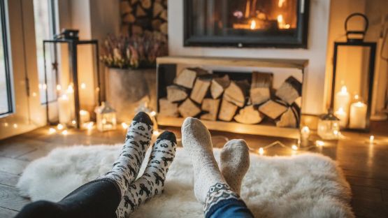 View of four feet in socks side by side in a cottage surrounded by candles