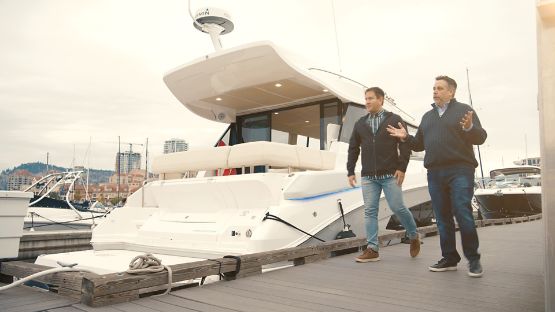 Two men walking on a dock beside a yacht 