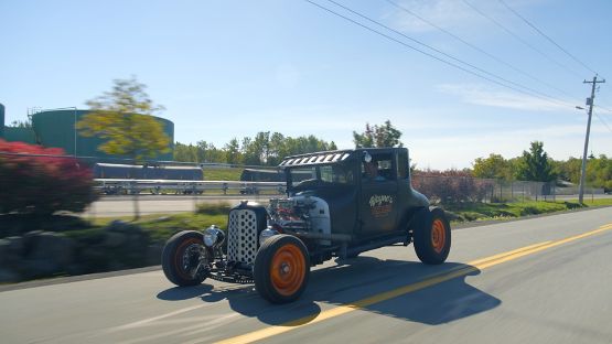 Classic black hot rod rod driving along a road